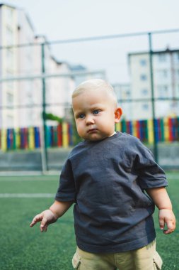 Parkta gezintiye çıkmış duygusal tatlı çocuk. 1 yaşında bir çocuk koşuyor ve gülümsüyor..