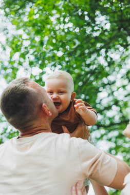 Sevimli baba küçük oğluyla oynuyor ve onu kollarında taşıyor. Baba oğul oyunu.