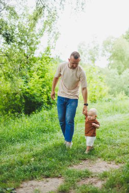 Genç bir baba oğluna ilk adımlarını atmasını öğretir. Baba ve oğul yürüyüşe çıktı..