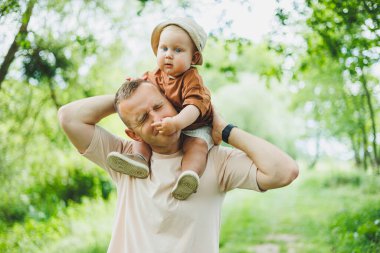 Sevimli baba küçük oğluyla oynuyor ve onu kollarında taşıyor. Baba oğul oyunu.