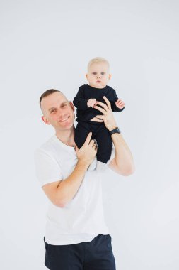 Sevimli baba küçük oğluyla oynuyor ve onu kollarında taşıyor. Baba oğul oyunu.