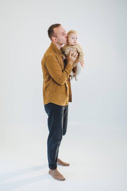 Sevimli baba küçük oğluyla oynuyor ve onu kollarında taşıyor. Baba oğul oyunu.