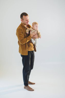 Sevimli baba küçük oğluyla oynuyor ve onu kollarında taşıyor. Baba oğul oyunu.