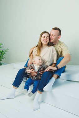 Küçük bir oğlu olan mutlu bir aile çifti. Anne, baba ve bebek sarılıyor..