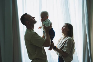 Küçük bir oğlu olan mutlu bir aile çifti. Anne, baba ve bebek sarılıyor..