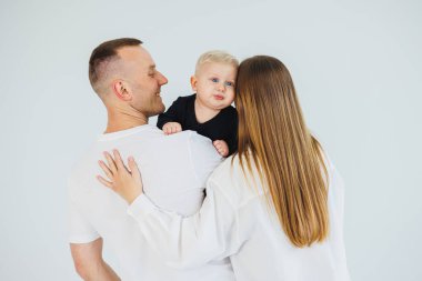 Küçük bir oğlu olan mutlu bir aile çifti. Anne, baba ve bebek sarılıyor..