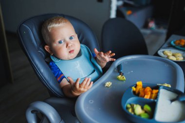 Küçük bir çocuk çatalla yemek yemeyi öğreniyor. Bebek maması. Çocuk kendi başına yemek yemeyi öğreniyor..