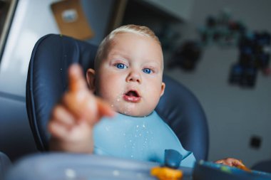 Küçük bir çocuk çatalla yemek yemeyi öğreniyor. Bebek maması. Çocuk kendi başına yemek yemeyi öğreniyor..