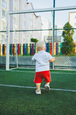 Yazın yürüyüşe çıkan beyaz tişörtlü ve şortlu bir çocuk. Çocuk koşuyor ve temiz havada oynuyor..