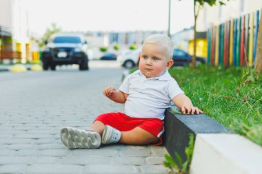 Yazın yürüyüşe çıkan beyaz tişörtlü ve şortlu bir çocuk. Çocuk koşuyor ve temiz havada oynuyor..