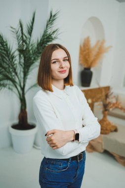 Evdeki parlak bir odada sevimli bir kadın duruyor. Günlük giysiler içinde bir kadın evde dinleniyor..