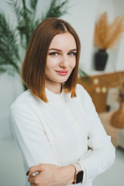 Evdeki parlak bir odada sevimli bir kadın duruyor. Günlük giysiler içinde bir kadın evde dinleniyor..