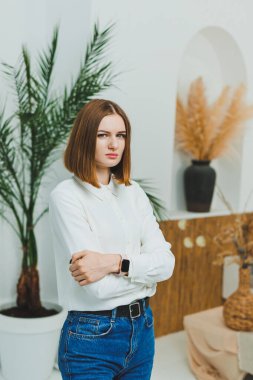 Evdeki parlak bir odada sevimli bir kadın duruyor. Günlük giysiler içinde bir kadın evde dinleniyor..