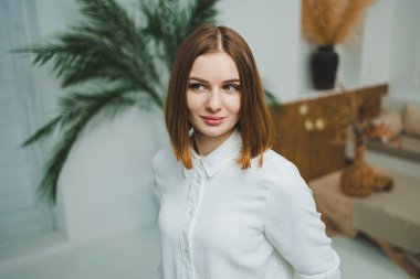 Evdeki parlak bir odada sevimli bir kadın duruyor. Günlük giysiler içinde bir kadın evde dinleniyor..