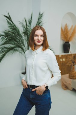 Evdeki parlak bir odada sevimli bir kadın duruyor. Günlük giysiler içinde bir kadın evde dinleniyor..