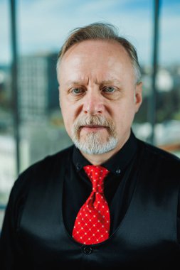 Siyah gömlekli, piercingli yaşlı bir adam. Sakallı bir iş adamının yakın plan portresi.