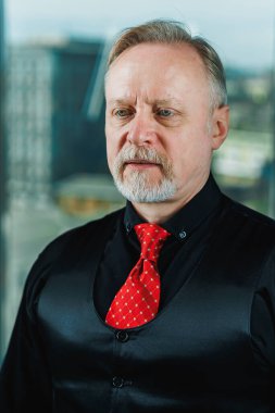 Siyah gömlekli, piercingli yaşlı bir adam. Sakallı bir iş adamının yakın plan portresi.