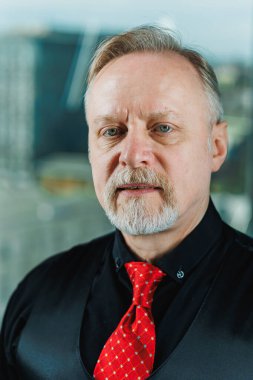 Siyah gömlekli, piercingli yaşlı bir adam. Sakallı bir iş adamının yakın plan portresi.