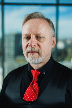 Siyah gömlekli, piercingli yaşlı bir adam. Sakallı bir iş adamının yakın plan portresi.