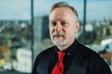 Siyah gömlekli, piercingli yaşlı bir adam. Sakallı bir iş adamının yakın plan portresi.