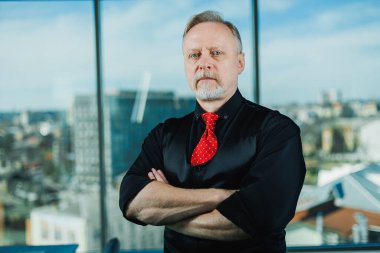 Siyah gömlekli, piercingli yaşlı bir adam. Sakallı bir iş adamının yakın plan portresi.