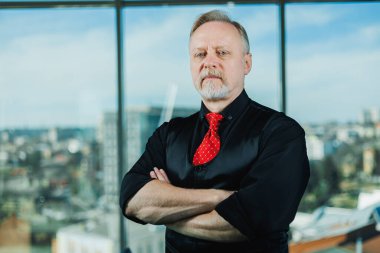 Siyah gömlekli, piercingli yaşlı bir adam. Sakallı bir iş adamının yakın plan portresi.