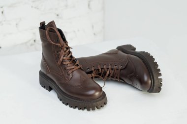 Stylish women's leather brown boots on white background, women's spring shoes close-up. Fashionable boots for women. Selective focus