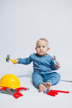 Beyaz bir arka planda küçük bir çocuk, bir inşaat setiyle oynuyor. Bebekler için oyuncaklar. Bir çocuk için plastik oyuncak seti