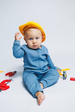 Beyaz bir arka planda küçük bir çocuk, bir inşaat setiyle oynuyor. Bebekler için oyuncaklar. Bir çocuk için plastik oyuncak seti