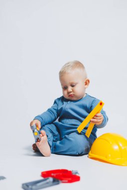Beyaz arka plandaki bebek, plastik çekiçle oynuyor. İnşaat için çocuk aletleri. Çocuk beyaz arka planda oyuncaklarla oynuyor
