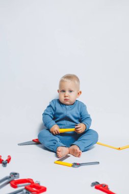 Beyaz arka plandaki bebek, plastik çekiçle oynuyor. İnşaat için çocuk aletleri. Çocuk beyaz arka planda oyuncaklarla oynuyor