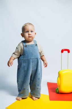 Küçük şirin çocuk bavuluyla oynuyor. Çantası olan küçük bir turist. Seyahat kavramı.