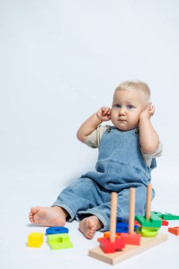 Bebek çocuk çocuk odasında oynarken bir bulmaca çözücüyle oynuyor. El becerilerini geliştirmek için oyuncaklar.