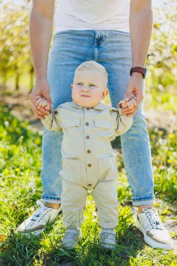 Küçük çocuk anne ve babasıyla el ele yürümeyi öğreniyor. İlk adımları atan çocuk.