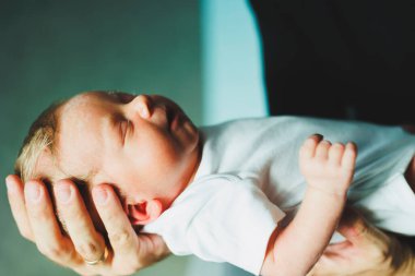 Bebeğin yakın çekimi anne ve babanın ellerinde. Küçük çocuk ailesinin kollarında.