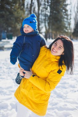 Mutlu anne küçük oğluyla kartopu oynuyor. Anne ve oğlunun kış yürüyüşü..