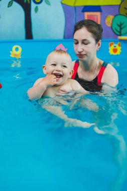 Bir çocuk bir koçla havuzda yüzmeyi öğrenir. Çocuklara yüzmeyi öğretmek..