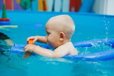 Bir koç erkek bebeğe yüzmeyi öğretir. Çocuklara yüzme öğretmek için yüzme havuzu.