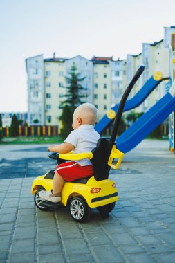 Küçük bir çocuk tolocar sürüyor. Bebekler için Tolokar. Kaymak için çocuk arabası..