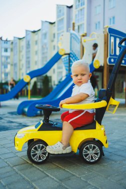 Küçük bir çocuk tolocar sürüyor. Bebekler için Tolokar. Kaymak için çocuk arabası..