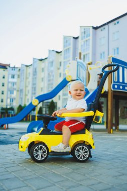 Küçük bir çocuk tolocar sürüyor. Bebekler için Tolokar. Kaymak için çocuk arabası..