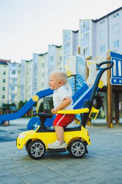 Küçük bir çocuk tolocar sürüyor. Bebekler için Tolokar. Kaymak için çocuk arabası..