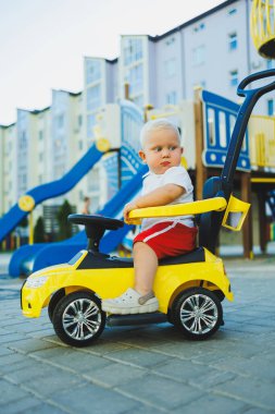 Küçük bir çocuk tolocar sürüyor. Bebekler için Tolokar. Kaymak için çocuk arabası..