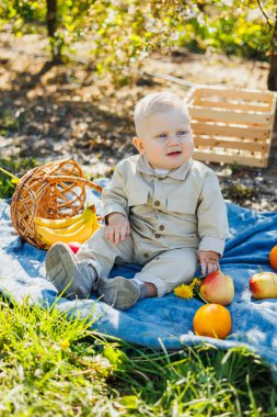 Küçük çocuk 1 yaşında parkta çimlerin üzerinde oturmuş ekmek yiyor. Bebek temiz havada yürüyüşe çıktı..