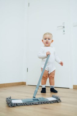 Tatlı çocuk paspasla yerleri yıkıyor, annesinin evi temizlemesine yardım ediyor. Çocuk evi temizlemeyi öğreniyor..