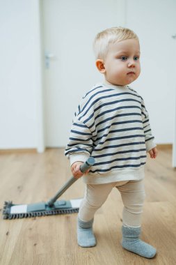 Tatlı çocuk paspasla yerleri yıkıyor, annesinin evi temizlemesine yardım ediyor. Çocuk evi temizlemeyi öğreniyor..