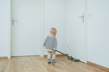 Küçük çocuk paspasla yerleri yıkıyor, annesinin evi temizlemesine yardım ediyor. Çocuk evi temizlemeyi öğreniyor..