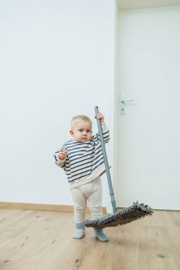 Evdeki yerleri temizleyen çocuk. Çocuk daireyi temizlemek için yerleri paspasla yıkıyor. Çocuklar evi temizlemeye yardım etmekten mutluluk duyarlar..