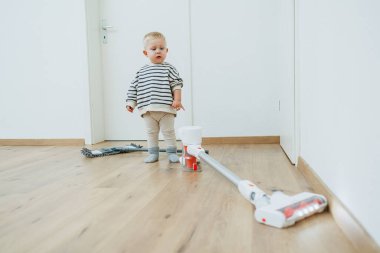 Evdeki yerleri temizleyen çocuk. Çocuk daireyi temizlemek için yerleri paspasla yıkıyor. Çocuklar evi temizlemeye yardım etmekten mutluluk duyarlar..