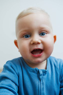 Yüzünde farklı duygular olan bir yaşındaki küçük bir çocuk. Duygusal bir bebek. Neşeli çocuk. Mavi gözlü küçük çocuk..